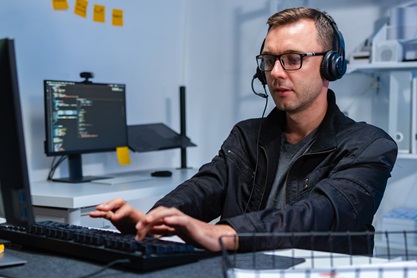 Mitarbeiter mit Headset an einem Arbeitsplatz mit zwei Monitoren