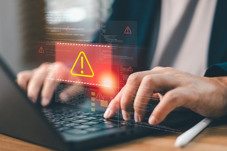 Hände an einem Laptop mit rotem Warnsymbol
