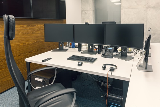 Büroarbeitsplatz mit drei Monitoren und Headset