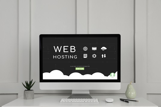 Monitor mit dem Schriftzug Web Hosting auf einem Schreibtisch